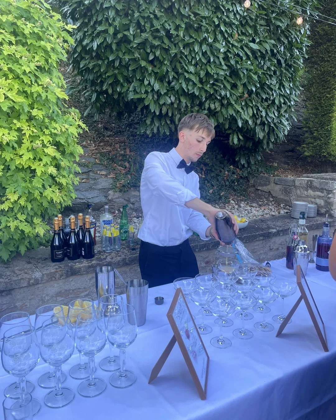 Le bar dressé en extérieur : nappe blanche, coupes empilées, shakers et fruits frais.