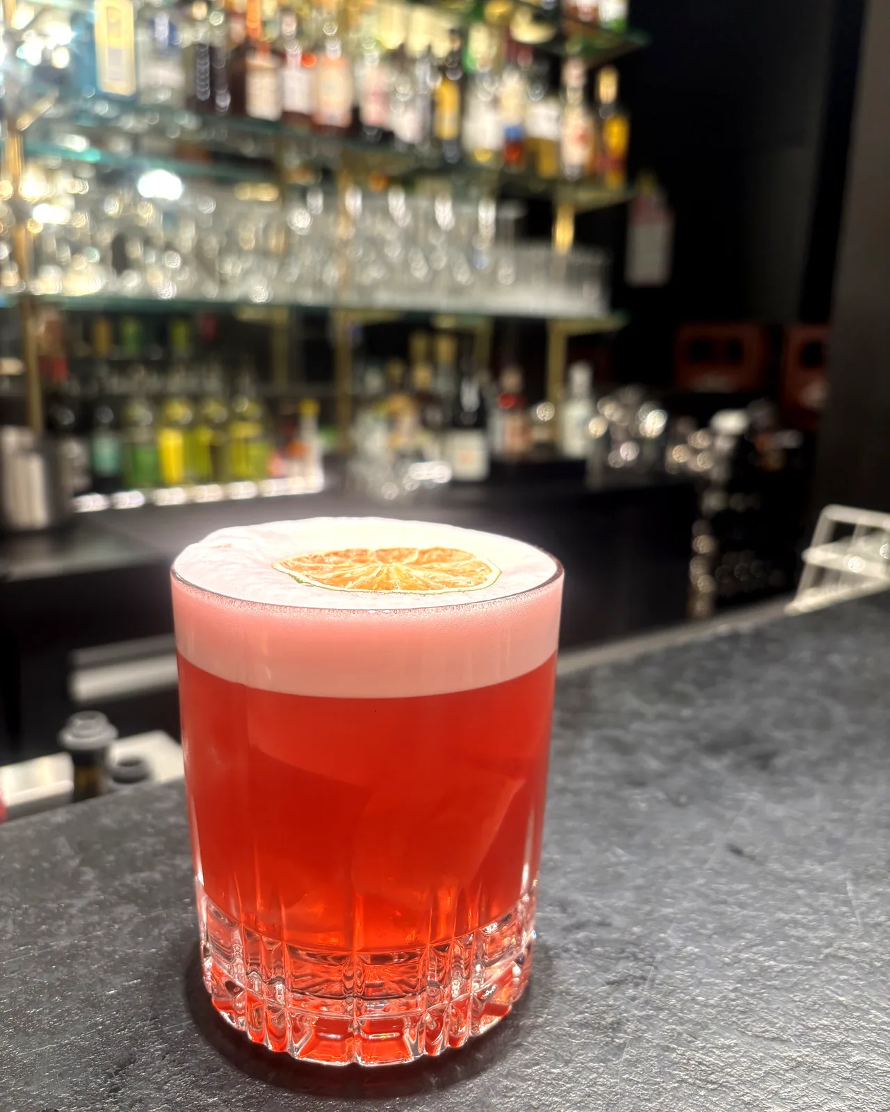 Aperol sour : cocktail orangé au col mousseux, rondelle d’orange séchée.